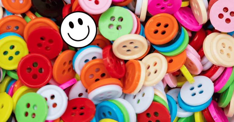 Many sewing buttons, one with a white smiley face